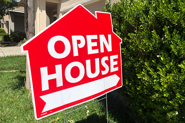 red sign shaped like a house that says open house