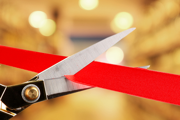 red ribbon being cut by scissors