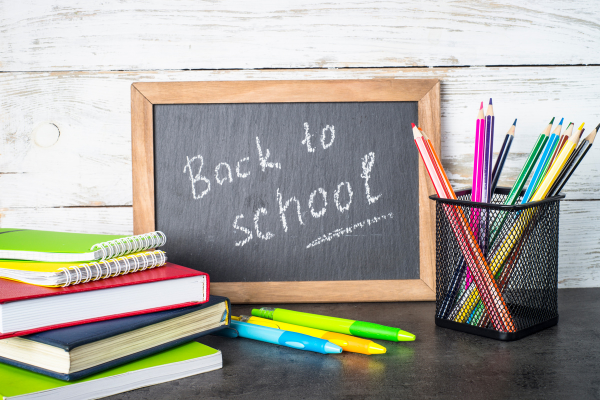 school supplies around a small black chalkboard that says back to school