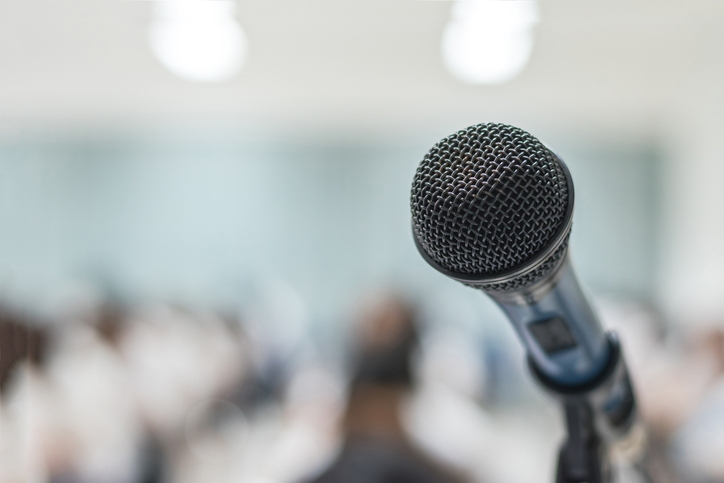 stock picture of a microphone in front of an audience